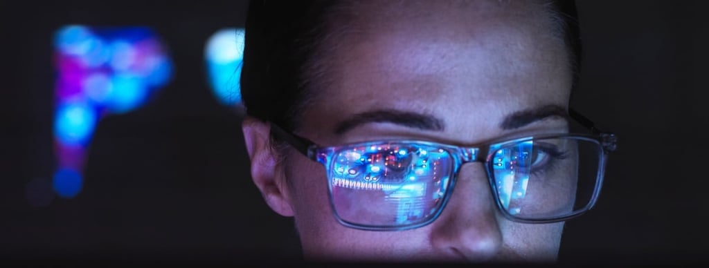Engineer designing AI technology with reflection on glasses